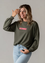 Sweat fin en coton porté par une femme, vue de trois-quarts, main sur la tête, jean