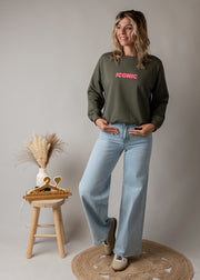 Sweat fin en coton porté par une femme, silhouette entière, tabouret, jean