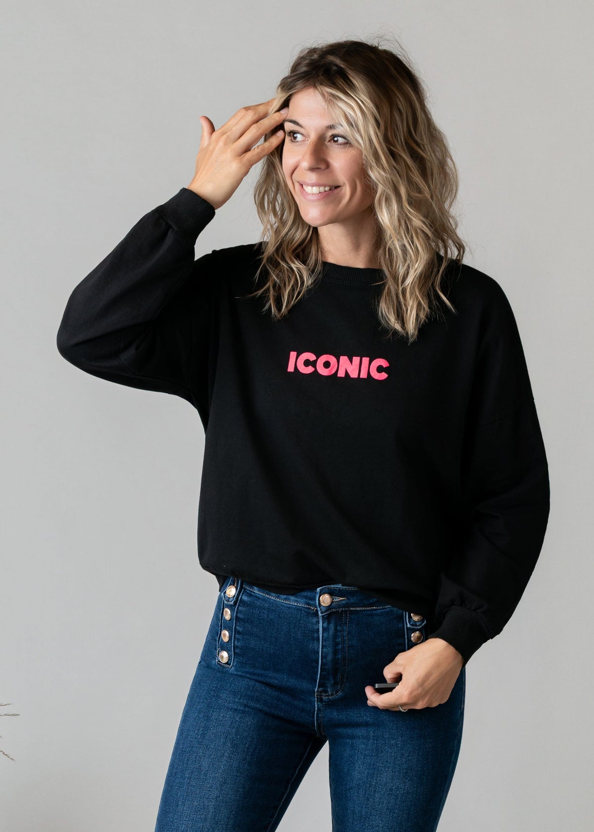 Sweat fin en molleton porté par une femme, vue de trois-quarts, main sur le front, jean