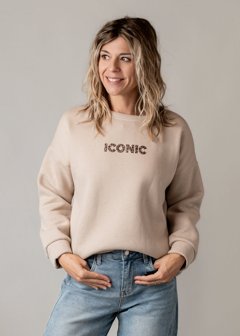 Sweat molletonné imprimé au dos porté par une femme, vue rapprochée, mains dans les poches, jean