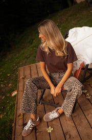 T-shirt large col rond chocolat porté par une femme, assise, terrasse, pantalon léopard