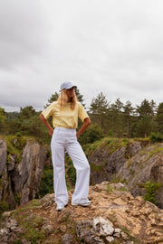 T-shirt ample col rond jaune porté par une femme, silhouette entière, rochers, casquette