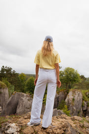 T-shirt ample col rond jaune porté par une femme, vue de dos, rochers, casquette