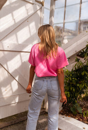 T-shirt ample manches courtes rose porté par une femme, vue de dos, serre, cheveux longs