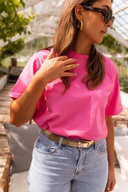 T-shirt ample manches courtes rose porté par une femme, vue rapprochée, ceinture, main sur le col