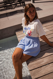 T-shirt imprimé col rond porté par une femme, assise, ponton, short bleu clair