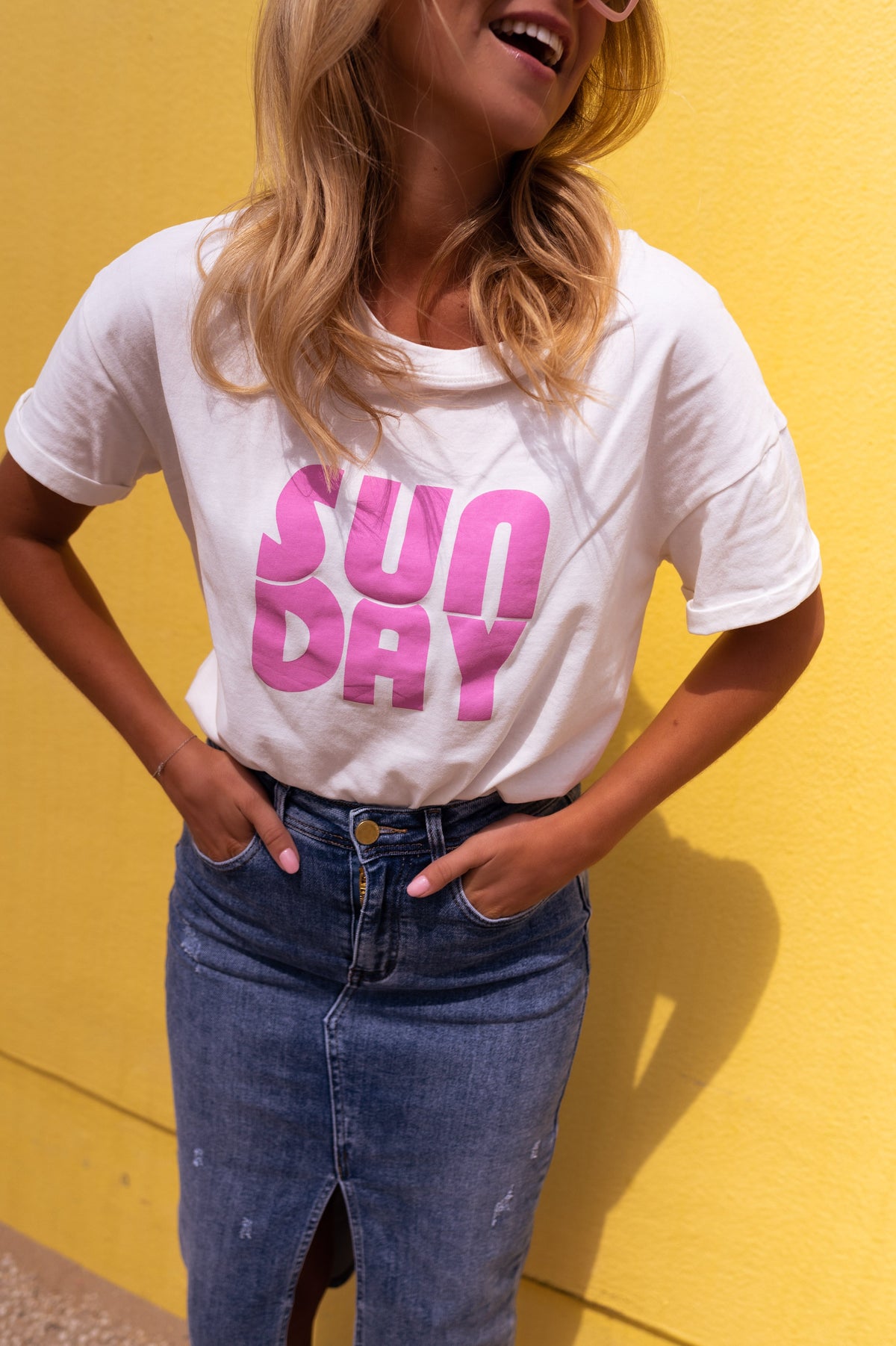 T-shirt doux col rond porté par une femme, vue rapprochée, t-shirt blanc imprimé rose, jupe en jean