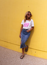 T-shirt doux col rond porté par une femme, vue de trois-quarts, mur jaune, lunettes