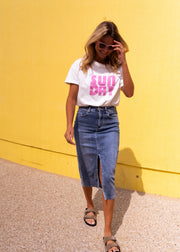 T-shirt doux col rond porté par une femme, silhouette entière, mur jaune, fente de la jupe