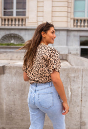 T-shirt léopard col rond porté par une femme, vue de dos, jean clair, balustrade