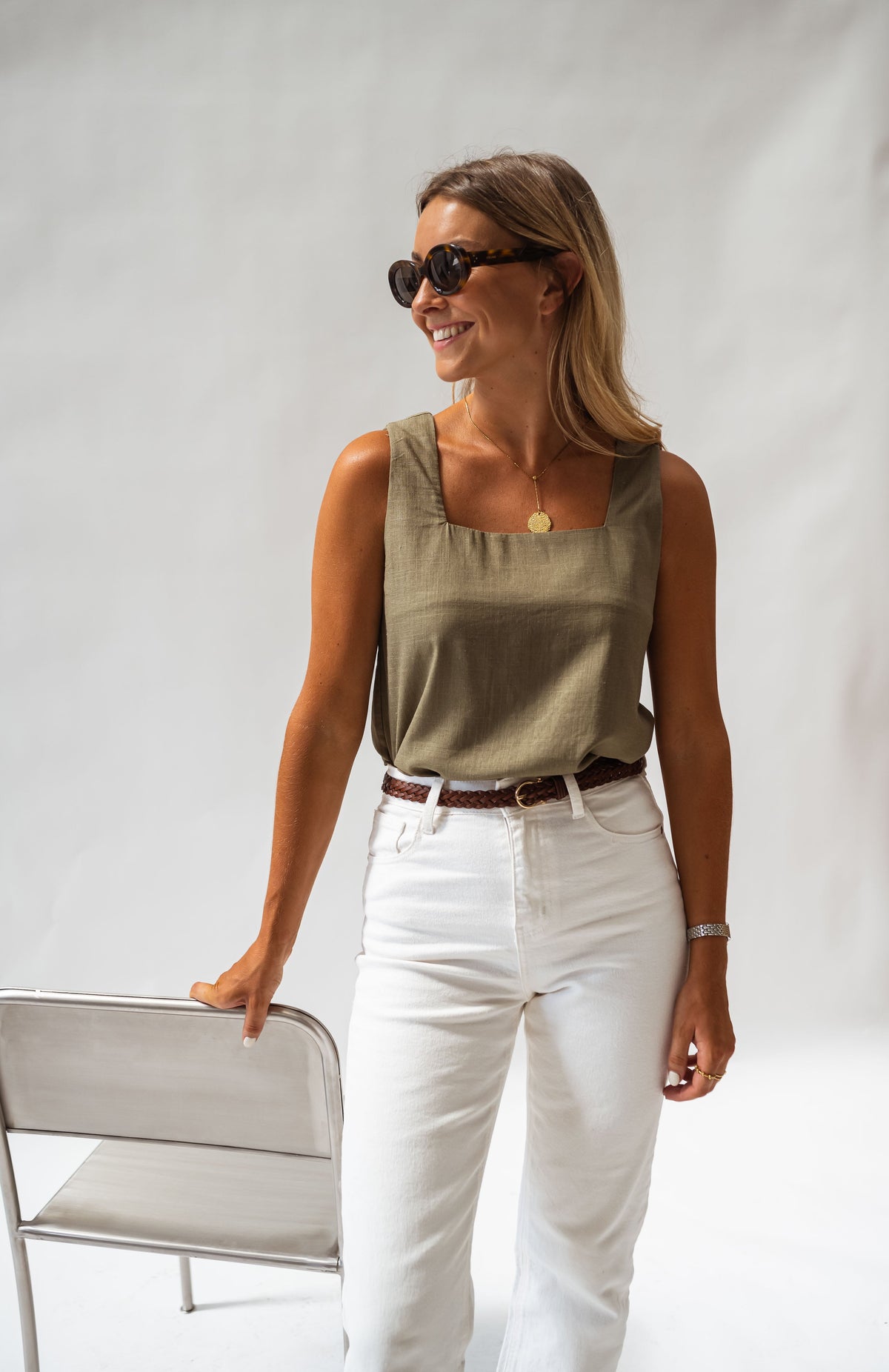 Top fluide col carré porté par une femme, silhouette entière, lunettes, pantalon blanc, ceinture