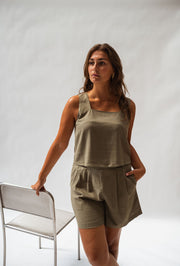 Top fluide col carré porté par une femme, silhouette entière, short kaki, chaise