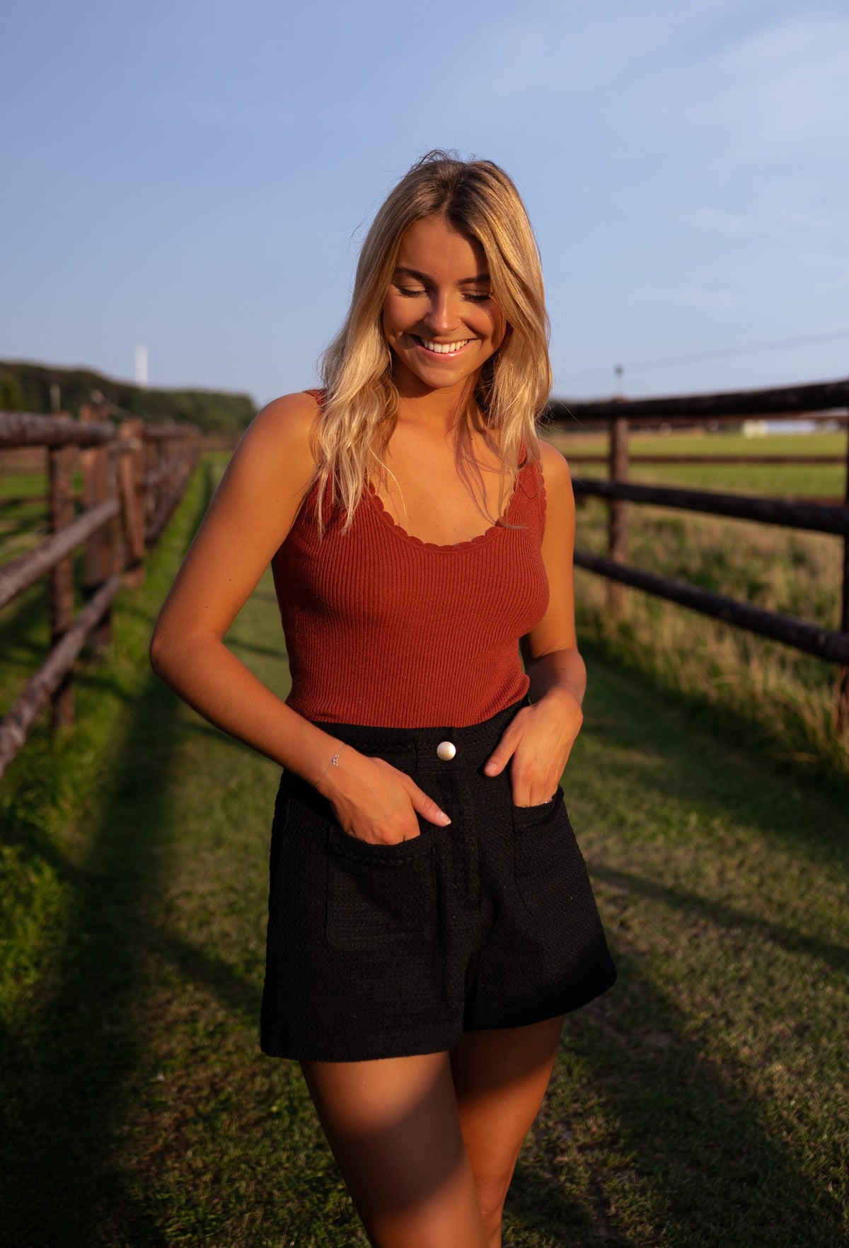 Top doux à décolleté carré porté par une femme, vue de trois-quarts, short noir, prairie