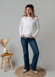 Top dentelle géométrique doublé porté par une femme, silhouette entière, jean flare, de face