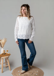 Top dentelle géométrique doublé porté par une femme, silhouette entière, jean flare, tabouret