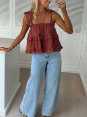 Top à volant col droit porté par une femme, silhouette entière, jean large, placard