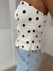 Top bustier à pois porté par une femme, vue rapprochée, pois noirs sur fond blanc