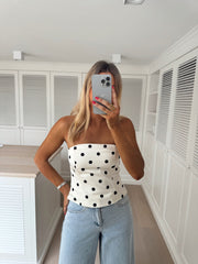 Top bustier à pois porté par une femme, silhouette entière, téléphone, jean clair
