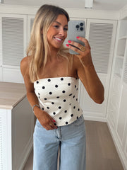 Top bustier à pois porté par une femme, vue de trois-quarts, téléphone, jean clair