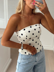 Top bustier à pois porté par une femme, vue de trois-quarts, téléphone, main sur la hanche