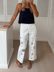 Top dos ouvert col droit porté par une femme, silhouette entière, pantalon blanc brodé de fleurs