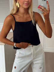 Top dos ouvert col droit porté par une femme, vue de trois-quarts, téléphone, pantalon blanc