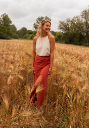 Top effet lin dos ouvert porté par une femme, silhouette entière, jupe orange, épis