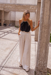 Top fluide à finition crochet porté par une femme, silhouette entière, piliers, main sur le pilier