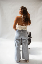 Top pailleté dos ouvert porté par une femme, vue de dos, fauteuil, jean large