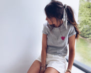 T-shirt à motif cœur porté par une femme, assise, de côté, short blanc