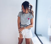 T-shirt à motif cœur porté par une femme, vue de trois-quarts, short blanc, queue de cheval
