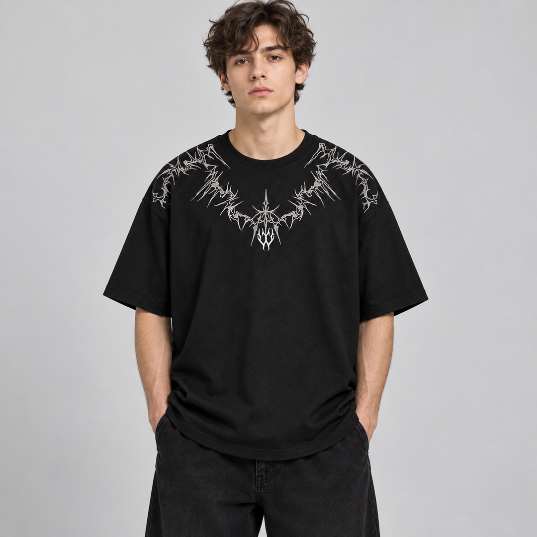 Homem com t-shirt preta larga de bordado branco no peito e ombros, vista frontal