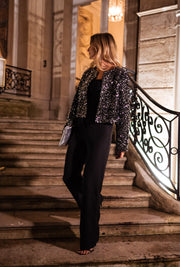 Veste en velours à paillettes portée par une femme, vue de profil, rampe en fer forgé, escalier