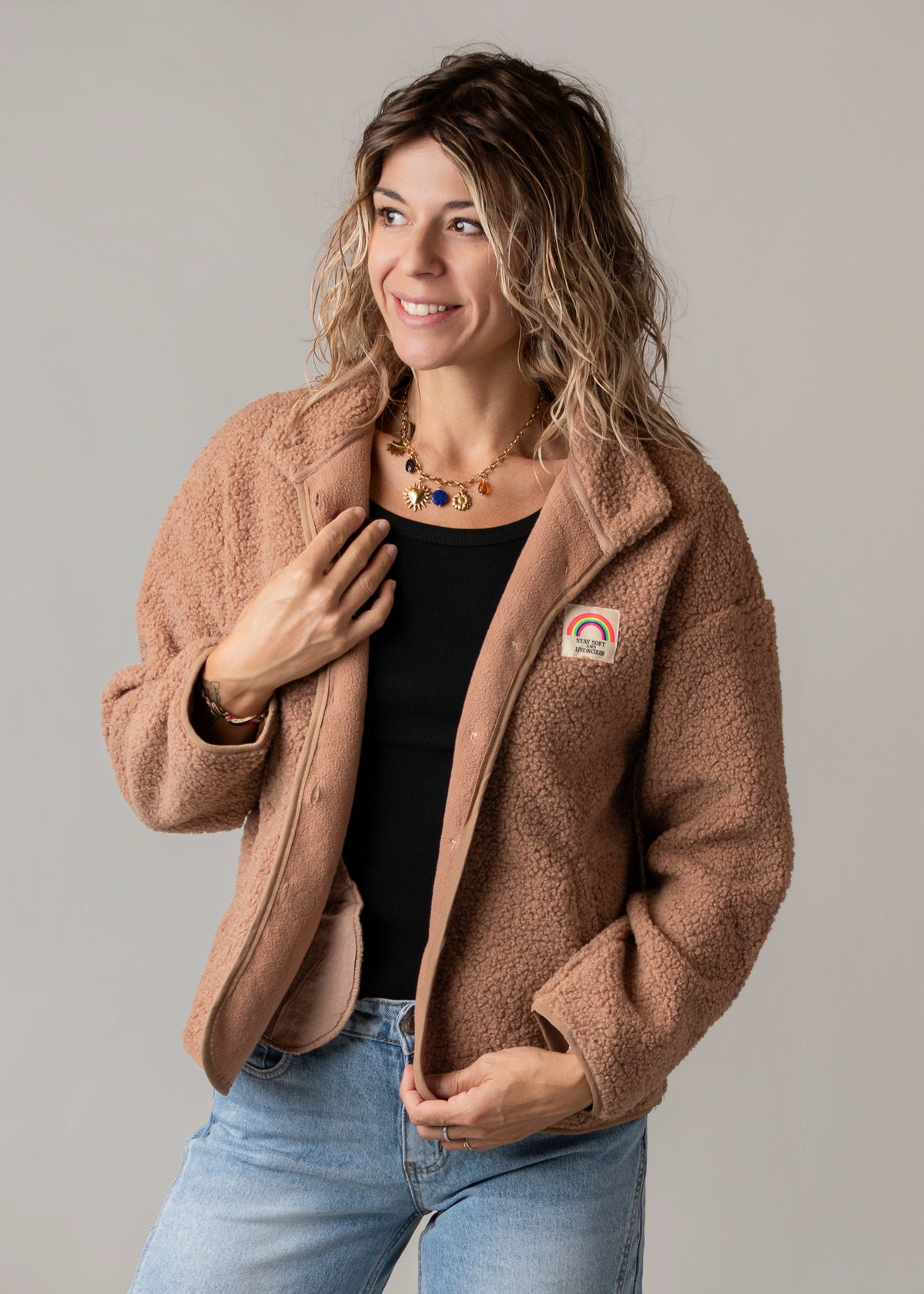 Veste bouclette doublée polaire portée par une femme, vue de trois-quarts, jean, fond gris