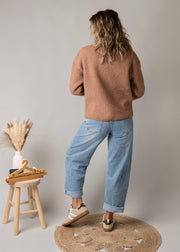 Veste sherpa doublée polaire portée par une femme, vue de dos, jean large, tabouret