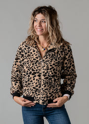 Veste bouclée zippée léopard portée par une femme, vue de trois-quarts, mains dans les poches, fond gris