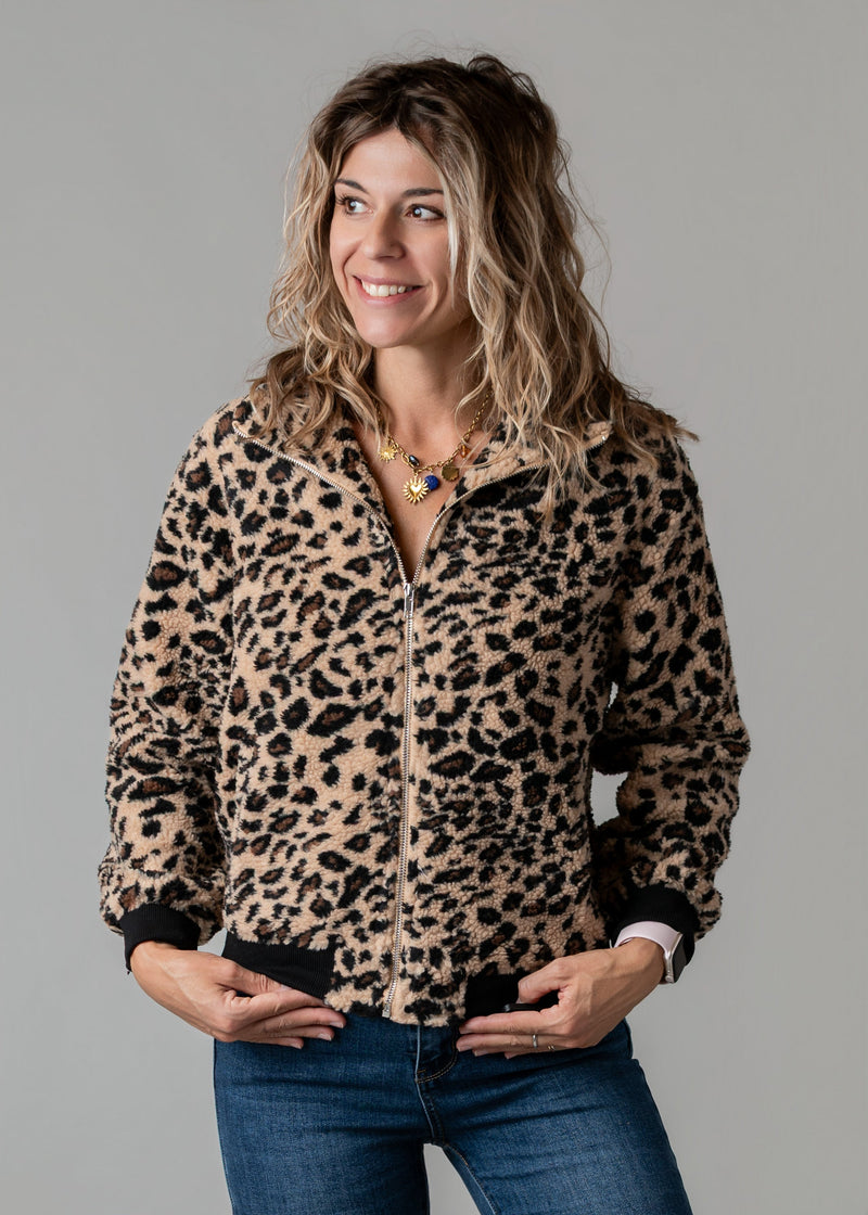 Veste bouclée zippée léopard portée par une femme, vue de trois-quarts, mains dans les poches, fond gris