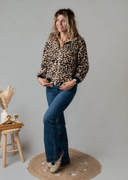 Veste bouclée zippée léopard portée par une femme, vue de trois-quarts, bottines, tabouret