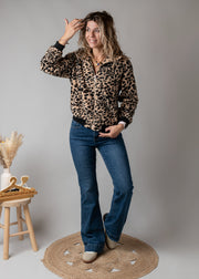 Veste bouclée zippée léopard portée par une femme, vue de trois-quarts, main dans les cheveux