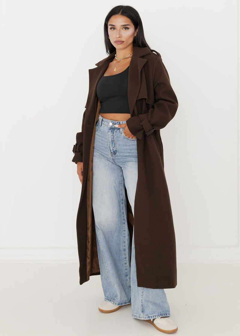 Trench brun foncé à ceinture — vue portée en pied, ouvert sur un haut noir et jean large clair