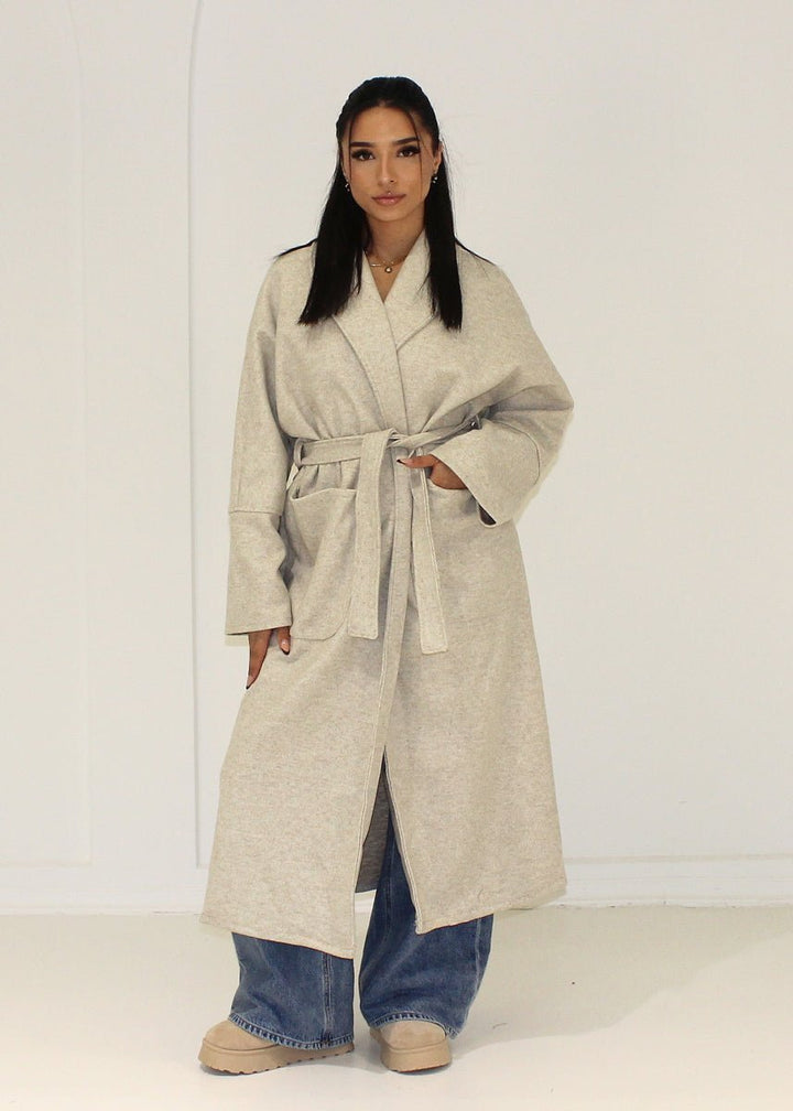Manteau long beige à poches plaquées — vue portée de face.